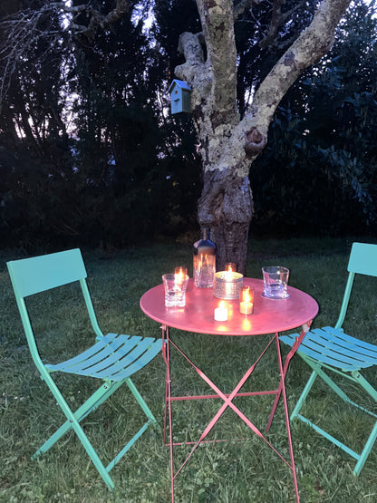 Table de terrasse élégante avec bougies LED rechargeables à lumière tamisée, verre et bouteille design pour un apéritif ou diner feutré et romantique au jardin.