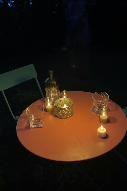 Bougies LED rechargeables créant une ambiance feutrée et complice autour d'une table  sur terrasse au crépuscule, 